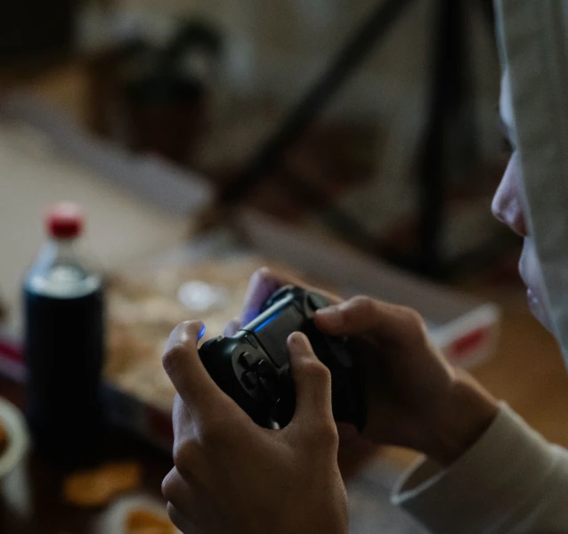 Jeune joueur de jeux vidéo entouré de nourriture déséquilibrée illustrant la négligence de la santé et des besoins essentiels